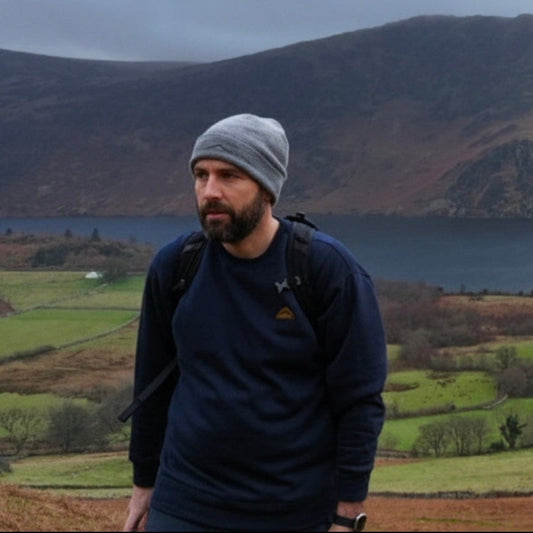 Man standing in a scenic landscape with mountains and a lake.
